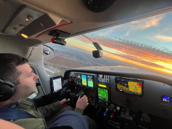 Pilot flying small airplane at sunset