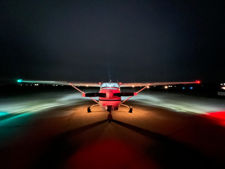 Small airplane on runway at night with lights